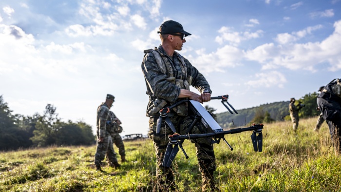 A soldier holding a drone in a field