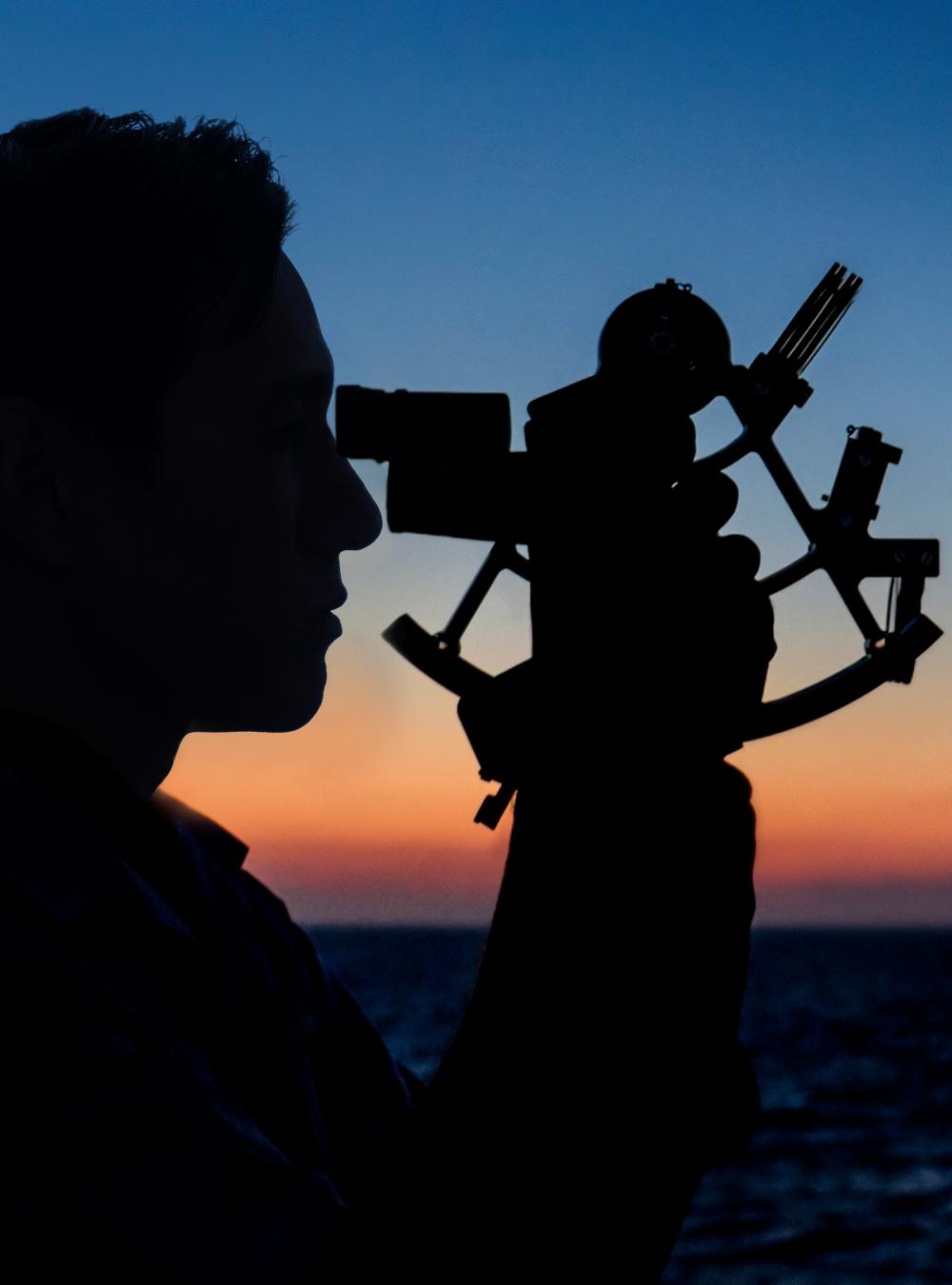 Silhouette of a person holding a sextant