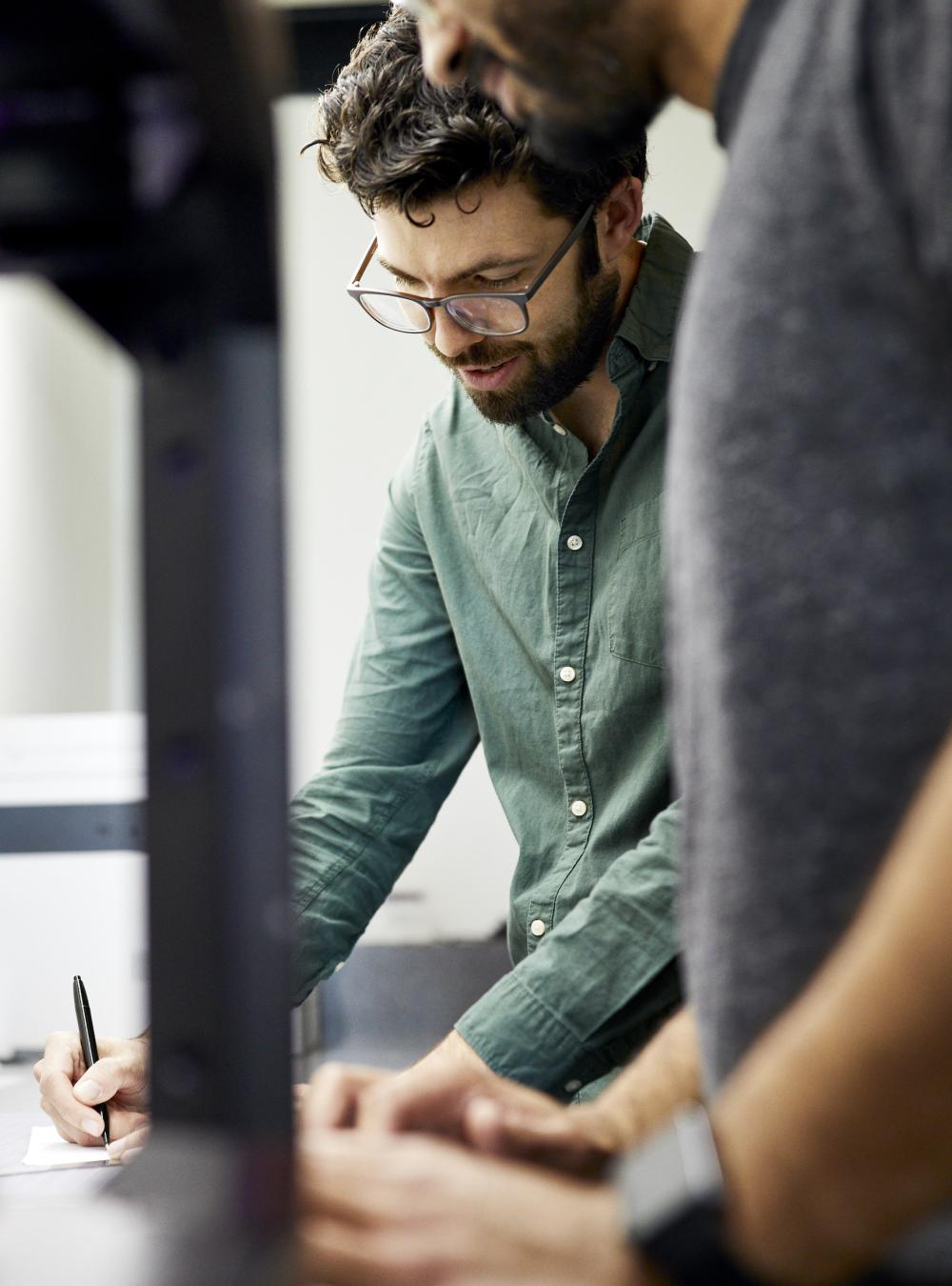 Military contractors working on a challenge, next to a 3D printer in a workspace