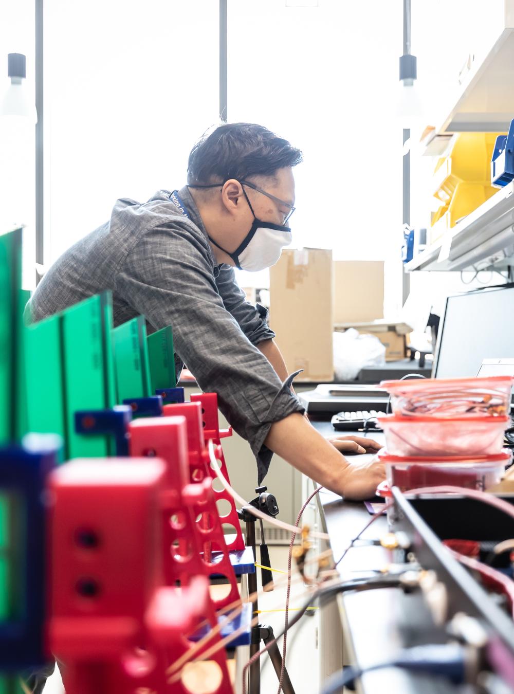 MITRE employee wearing a mask while working in a lab