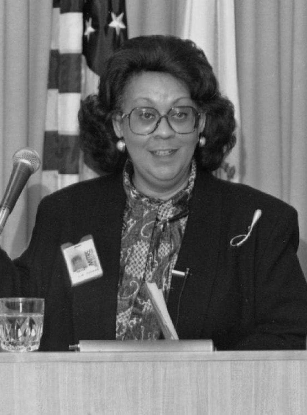 Black and white image of Lydia Thomas speaking at a podium