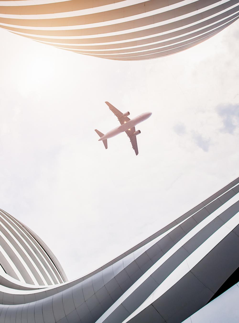 Airplane flying overhead, viewed from the courtyard of a modern building