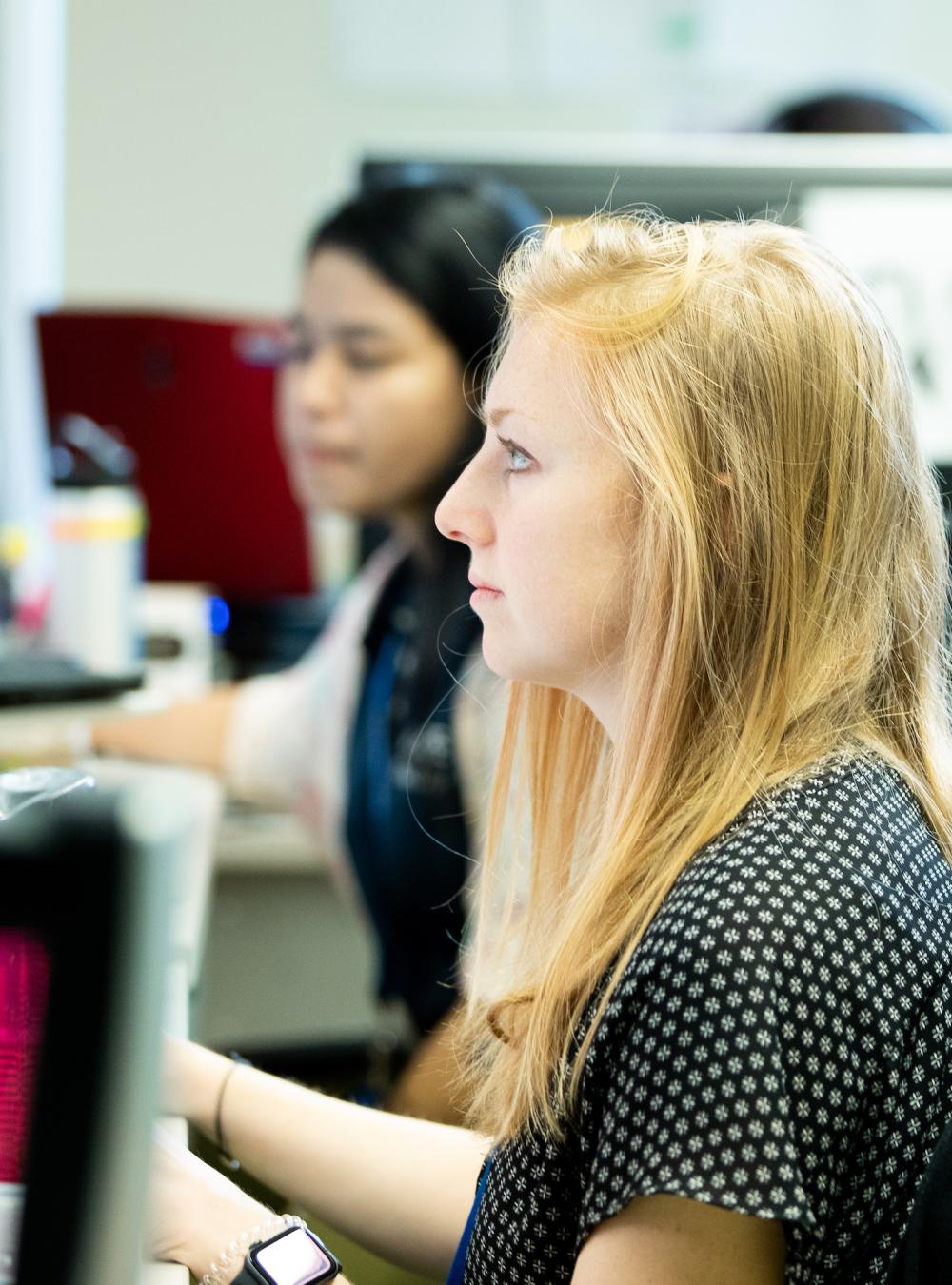 Two professional women focused intently while working in their office