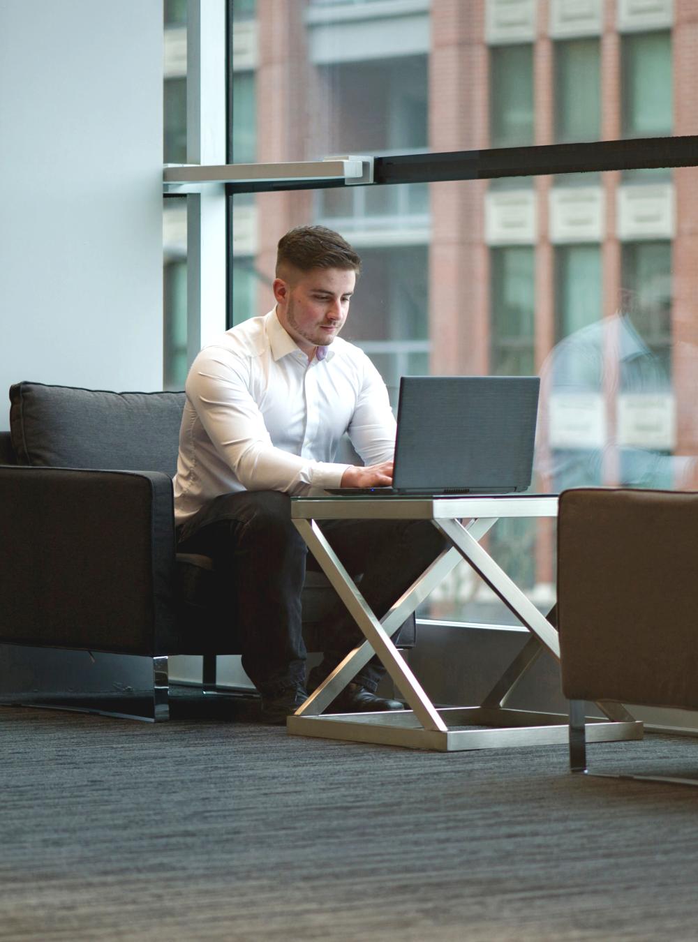 Early career professional working on a laptop in an open work space