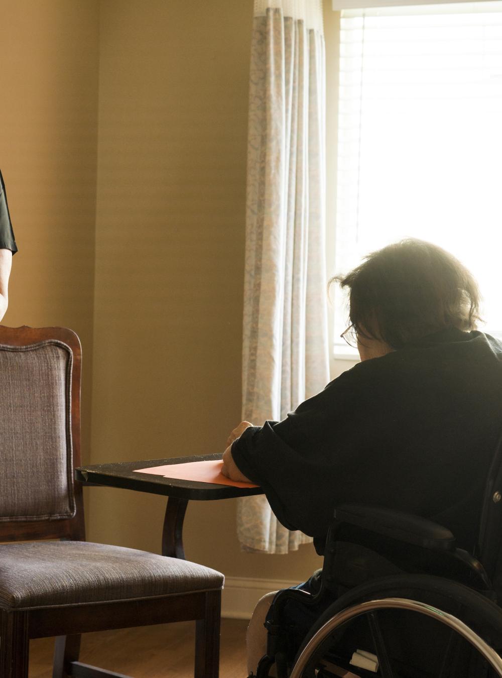 Provider assisting a resident at a nursing home who is in a wheelchair