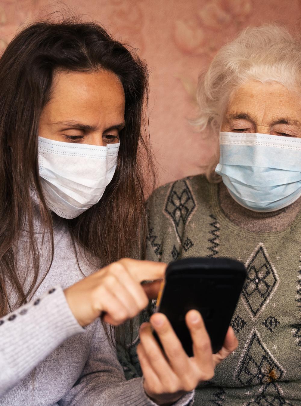 Yonger woman helping an older woman use a smartphone