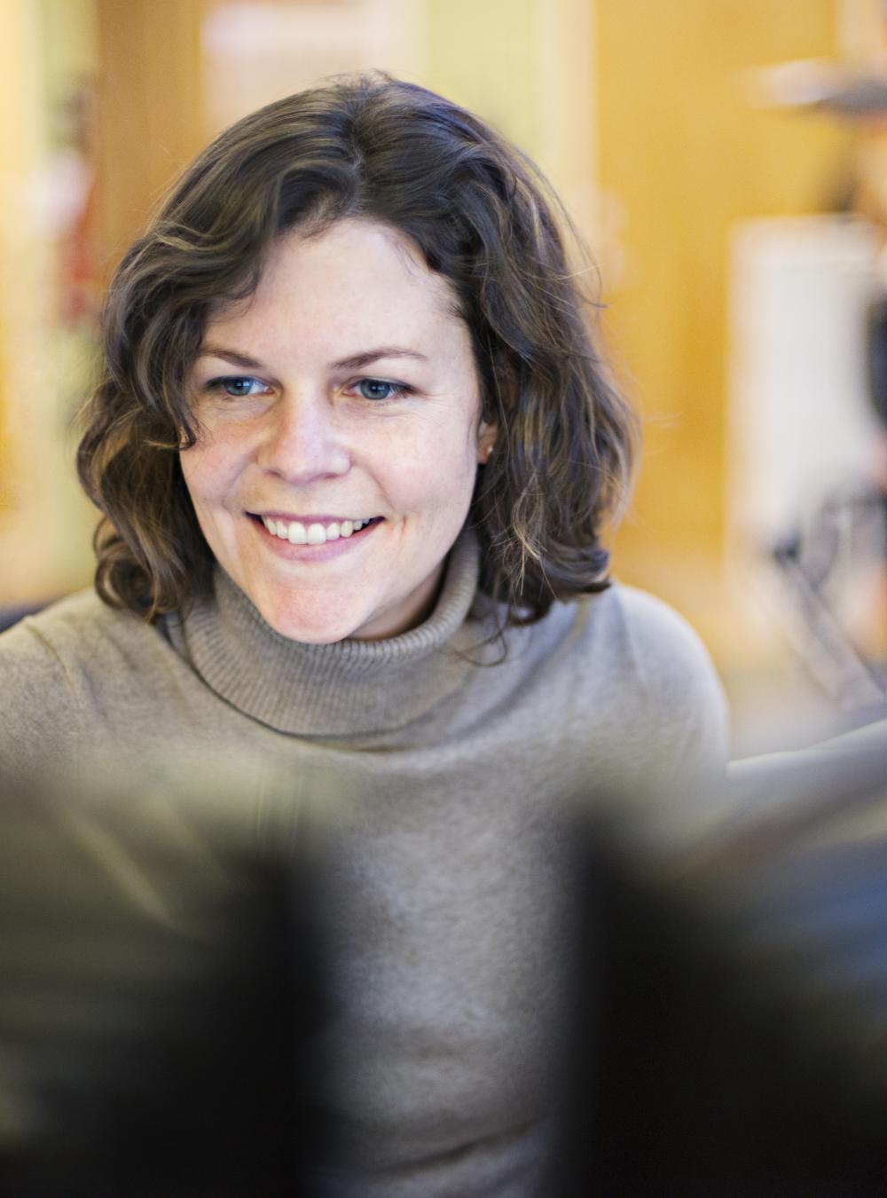 Woman excitedly working in a lab, looking at two monitors as she engages on a virtual call