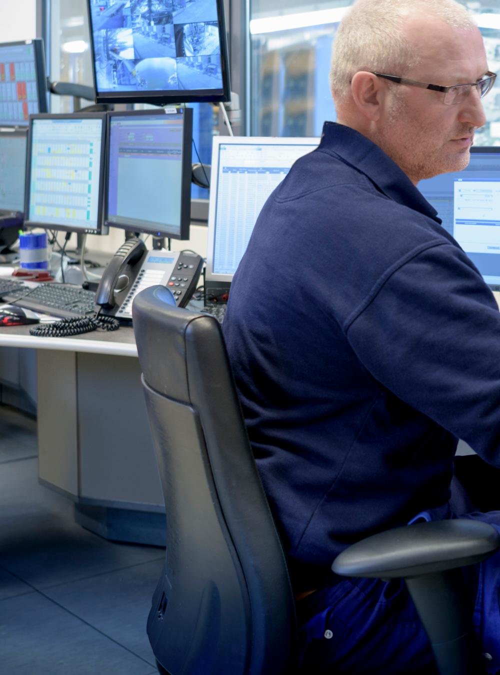 Workers in a control room surrounded by computer monitors