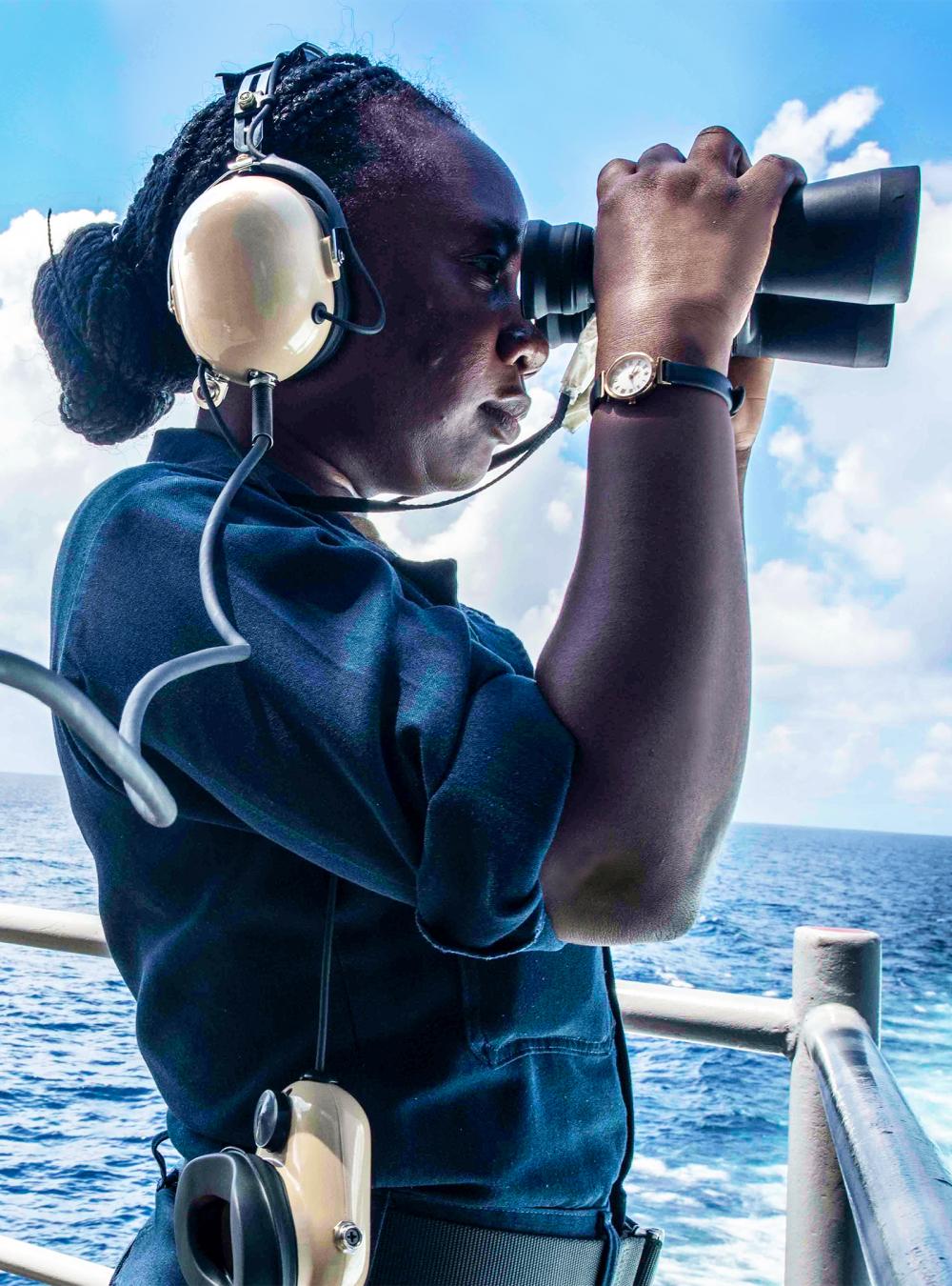 Navy officer on a ship looking through binoculars