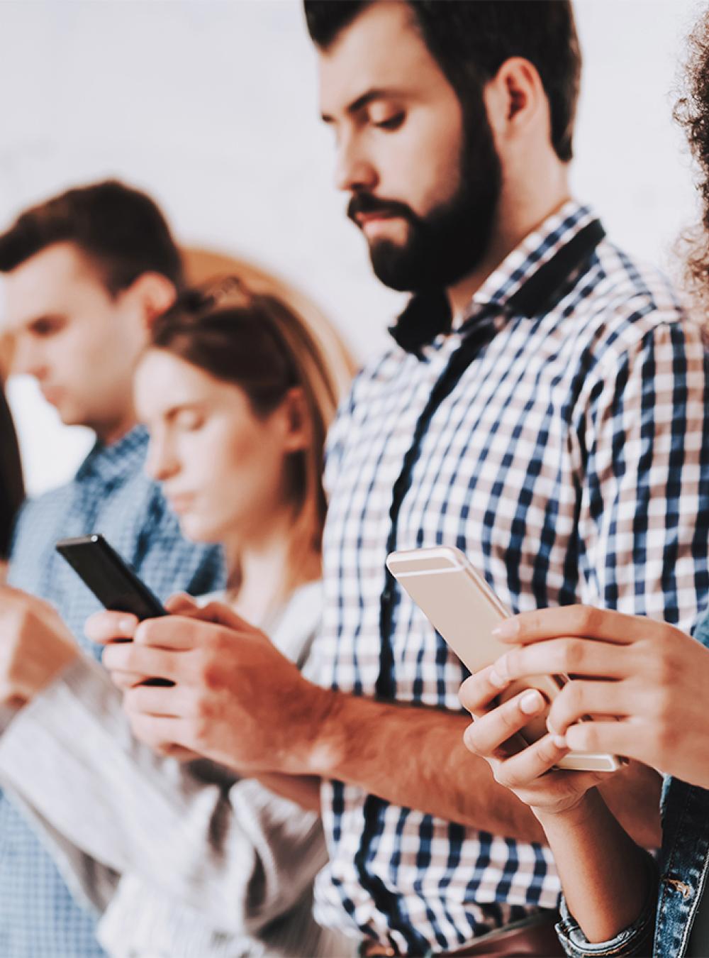 Row of standing people looking at mobile phones