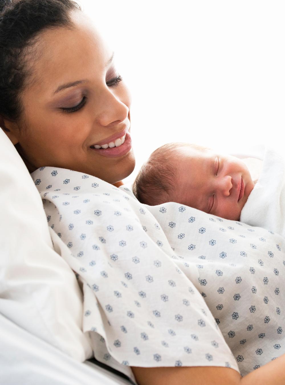 Mother in hospital bed holding newborn baby son