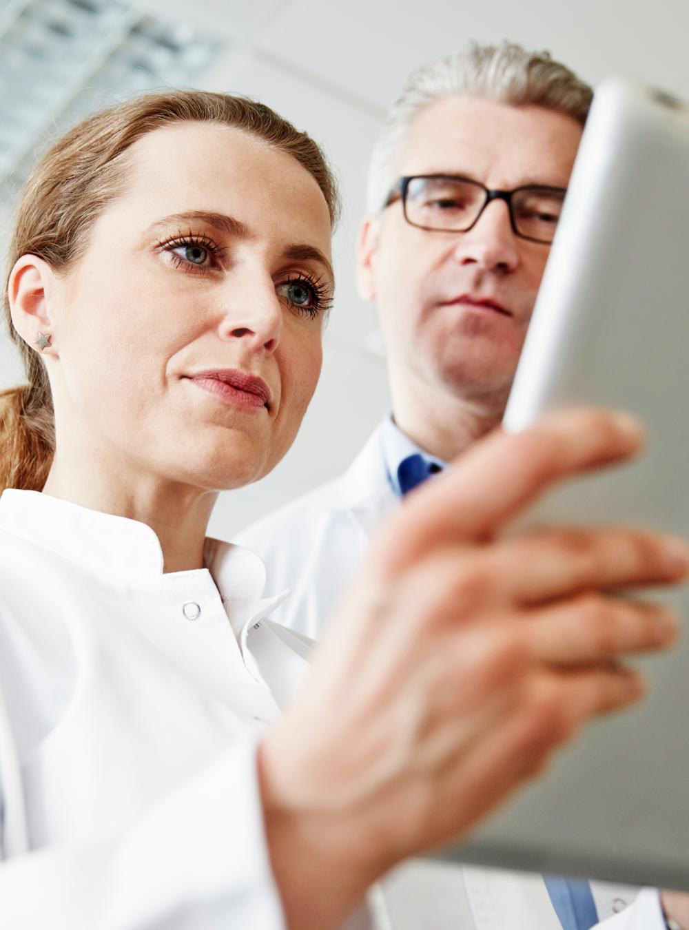 Three scientists in a laboratory, using a tablet