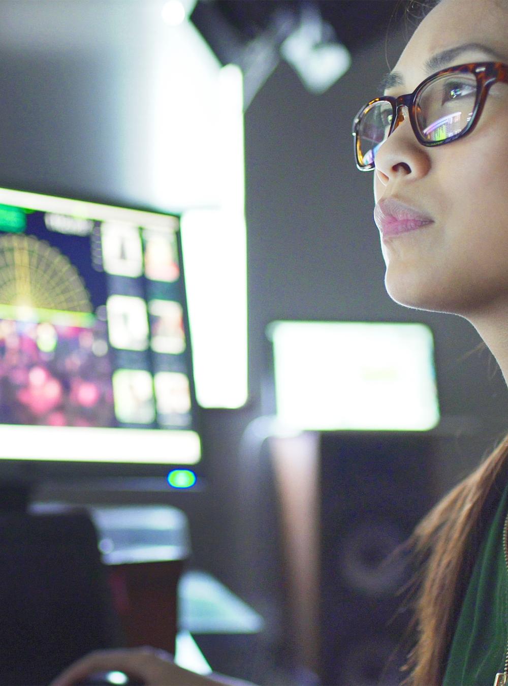 Woman sitting at her desk surrounded by 3 large computer monitors