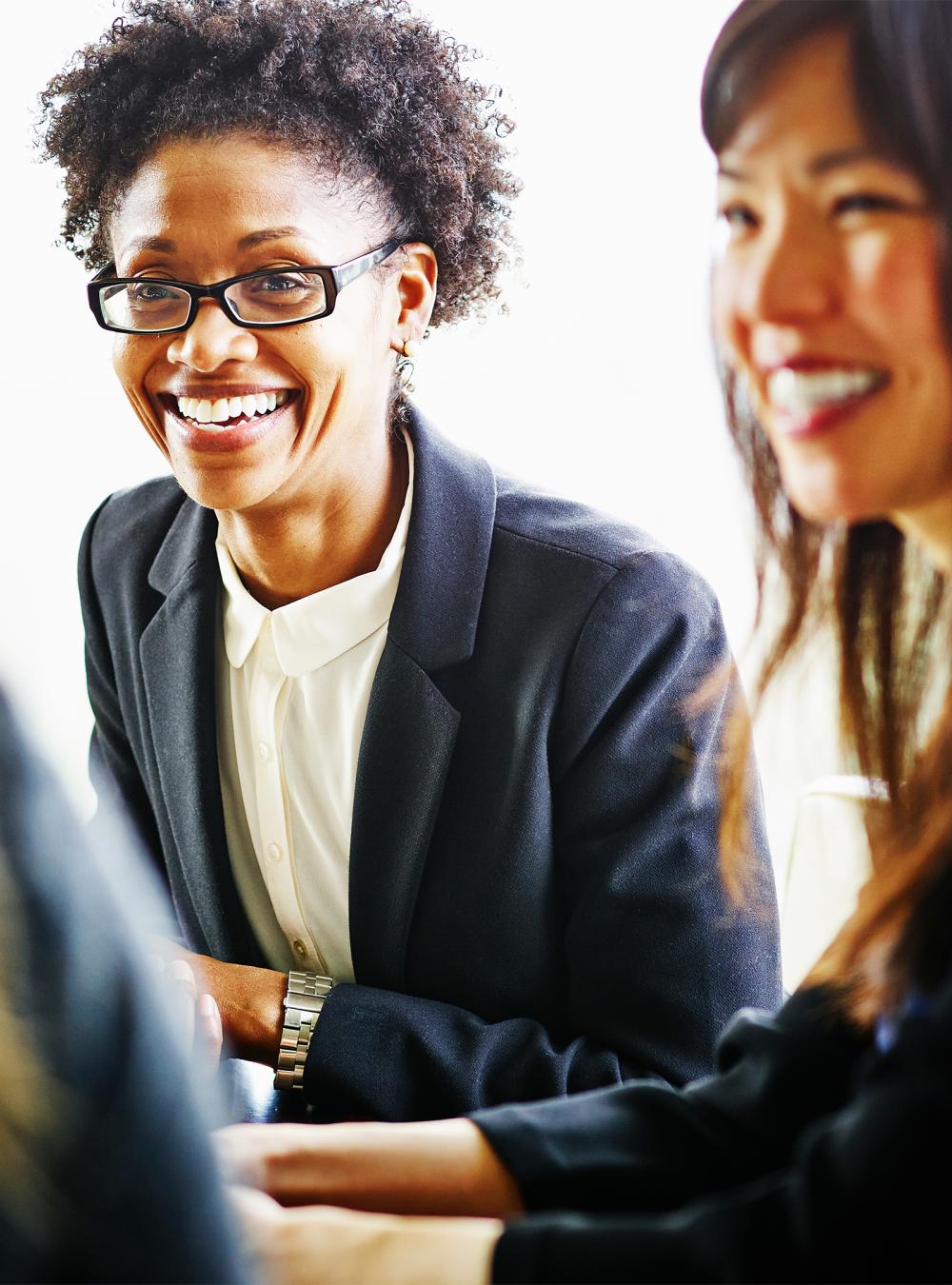 Smiling businesswoman discussing project with coworkers in conference room