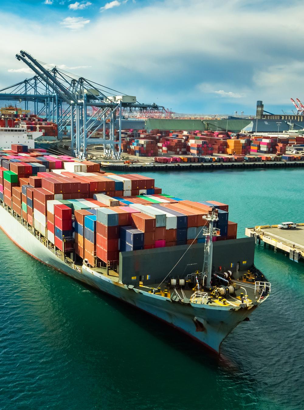 Tug boat maneuvering cargo ship at dockside in Port of Long Beach