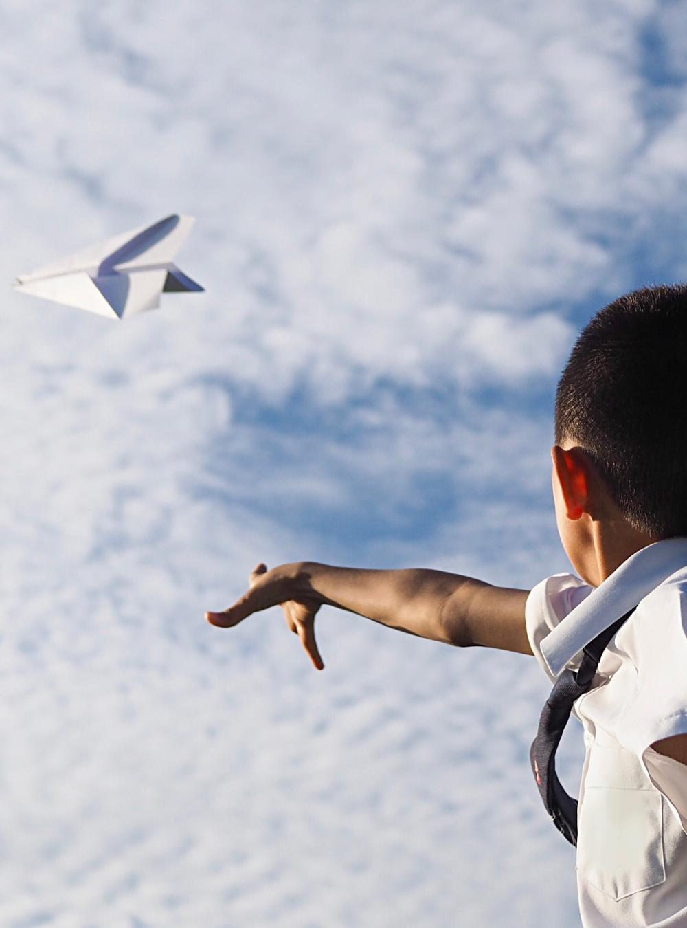 boy throwing paper airplane