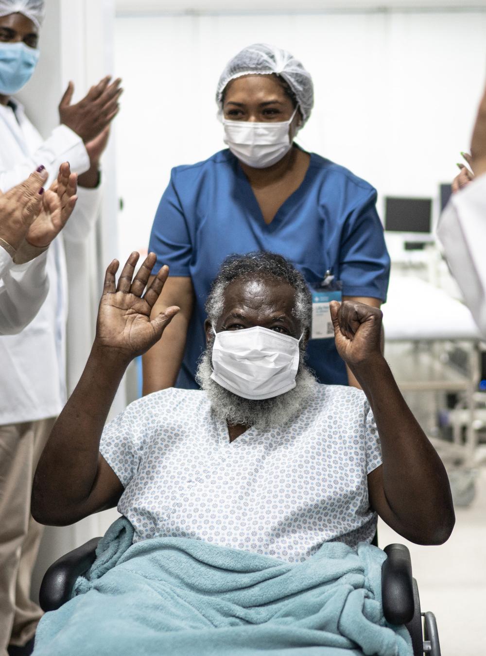 medical staff cheering patient in wheelchair