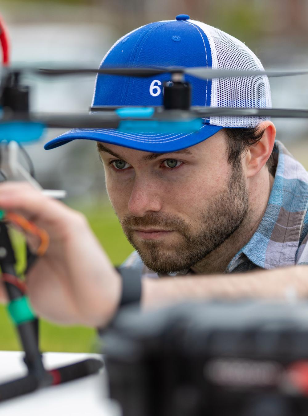 man with baseball hat working on a drone