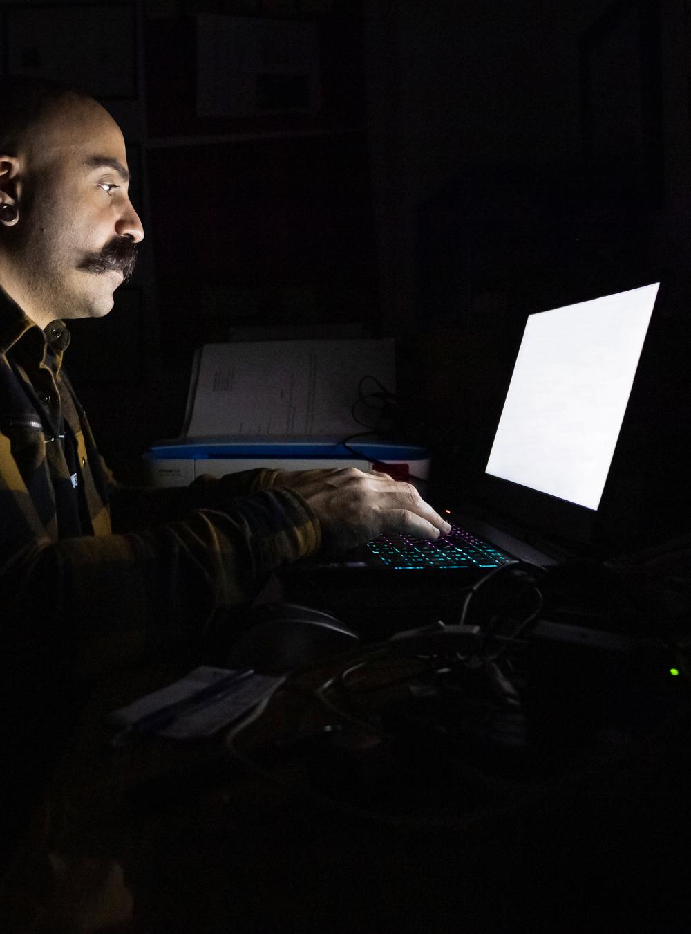 Man in a dark room on a laptop