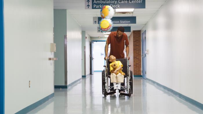 Father wheeling his child down the hall of a hospital