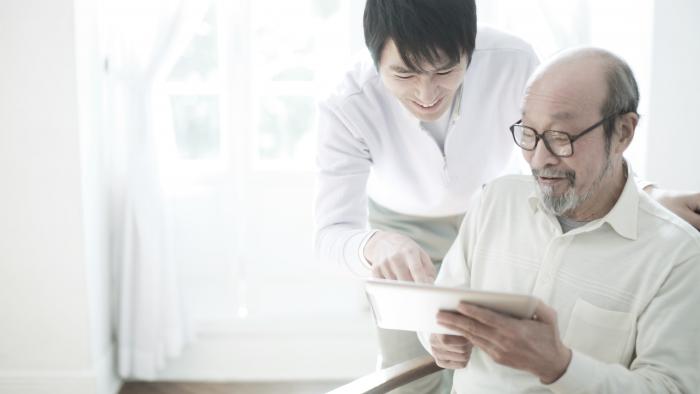 Father and his adult son looking at a tablet screen