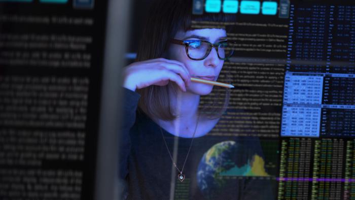 Woman in glasses analyzes data in a dark room