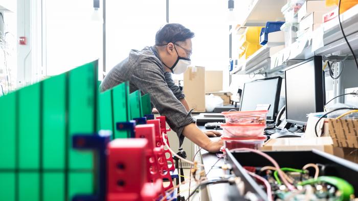 MITRE employee wearing a mask while working in a lab