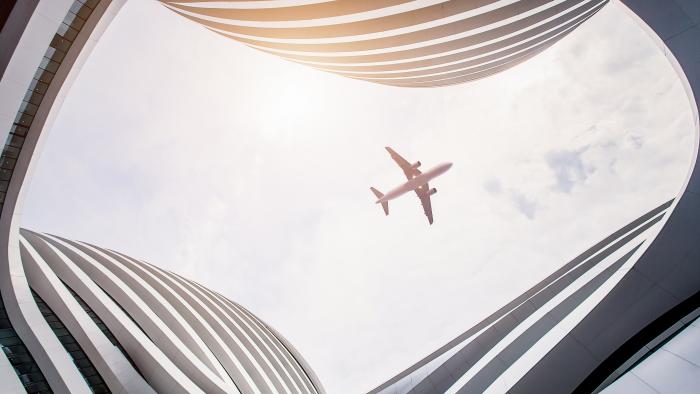 Airplane flying overhead, viewed from the courtyard of a modern building