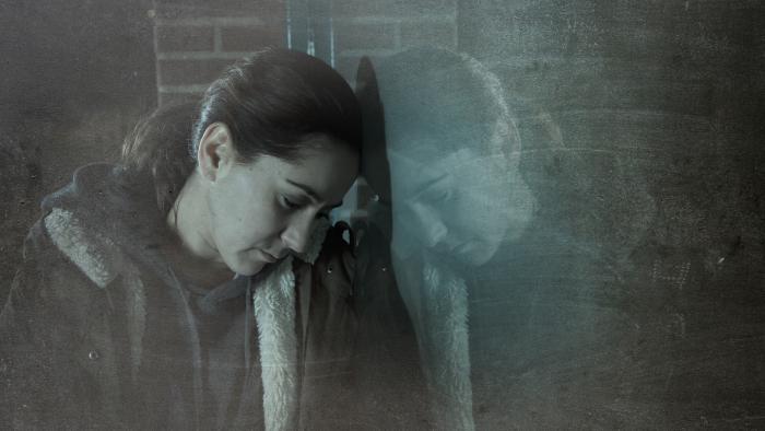 Woman leans against a wall in despair, appearing to need help and support