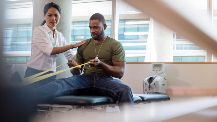 Veteran doing physical therapy supported by a therapist