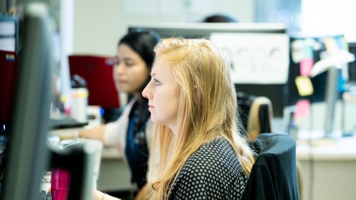 Two professional women focused intently while working in their office