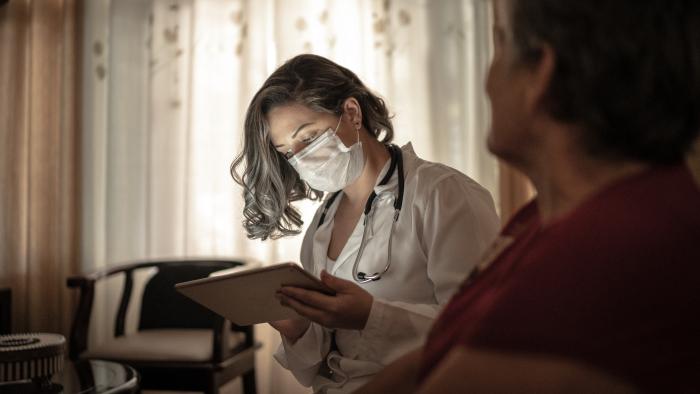 Doctor treating a nursing home resident in her living space