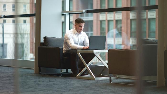 Early career professional working on a laptop in an open work space