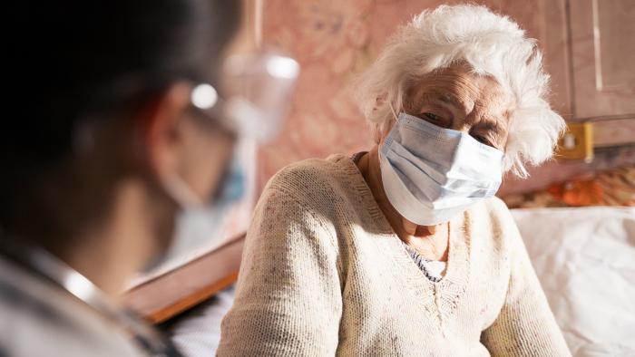 Doctor and elderly nursing home patient, both wearing masks