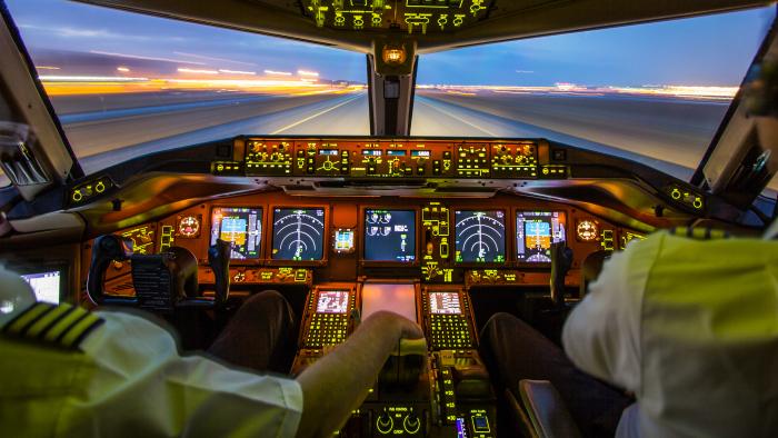 Two pilots in a lit up cockpit of an aircraft about to take off