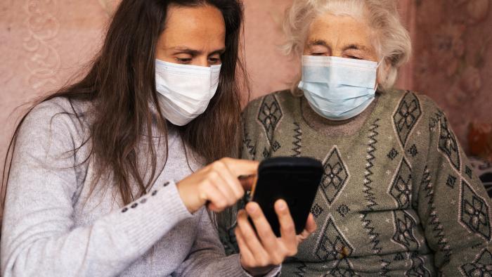 Yonger woman helping an older woman use a smartphone