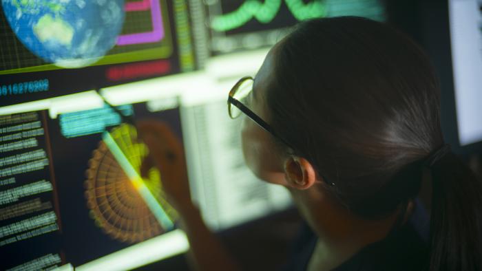 Woman working in the intelligence field, viewing monitors of data