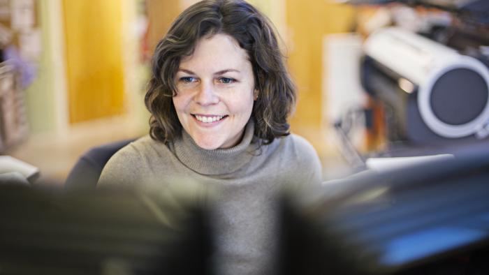 Woman excitedly working in a lab, looking at two monitors as she engages on a virtual call