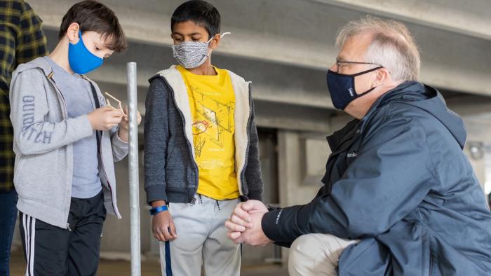 Students from Sangster Elementary School in Springfield, Virginia, examine a piece of their balsa structure with MITRE's Robert Kobee