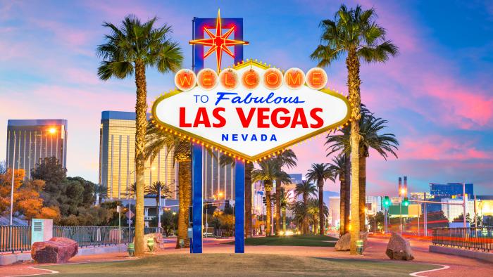 The Las Vegas Nevada sign with buildings and palm trees behind it