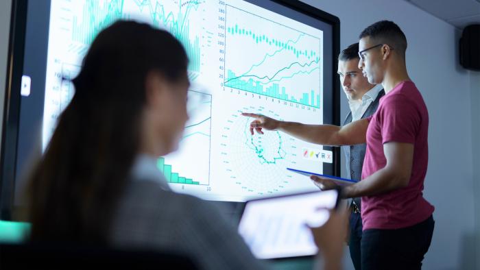 people in conference room with tablets and large wall display