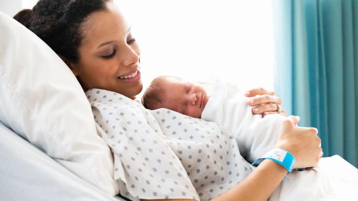 Mother in hospital bed holding newborn baby son