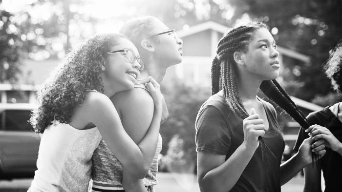 Teenage girl embracing friend while hanging out in neighborhood