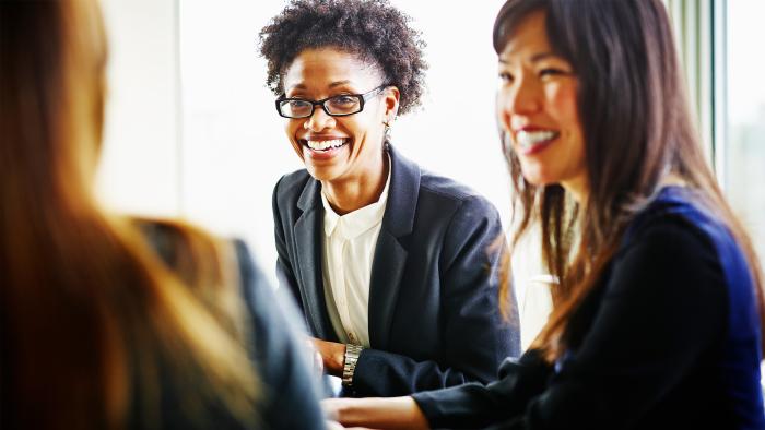 Smiling businesswoman discussing project with coworkers in conference room