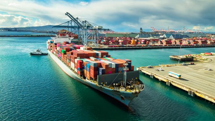 Tug boat maneuvering cargo ship at dockside in Port of Long Beach