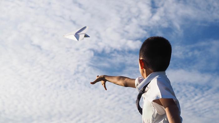 boy throwing paper airplane