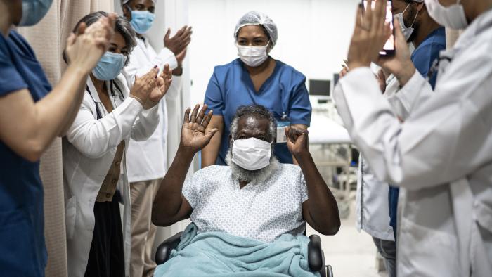 medical staff cheering patient in wheelchair