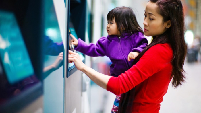 Mother and daughter using a banking machine outside