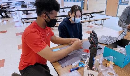 Khalif Mitchell helps a girl build a robotic hand