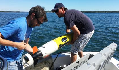 two men launching a sensor off a boat